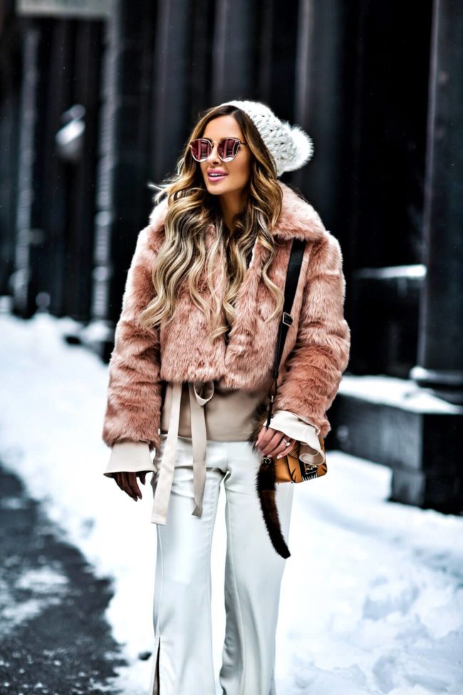 fashion blogger mia mia mine wearing a faux fur coat from asos and white pants from revolve