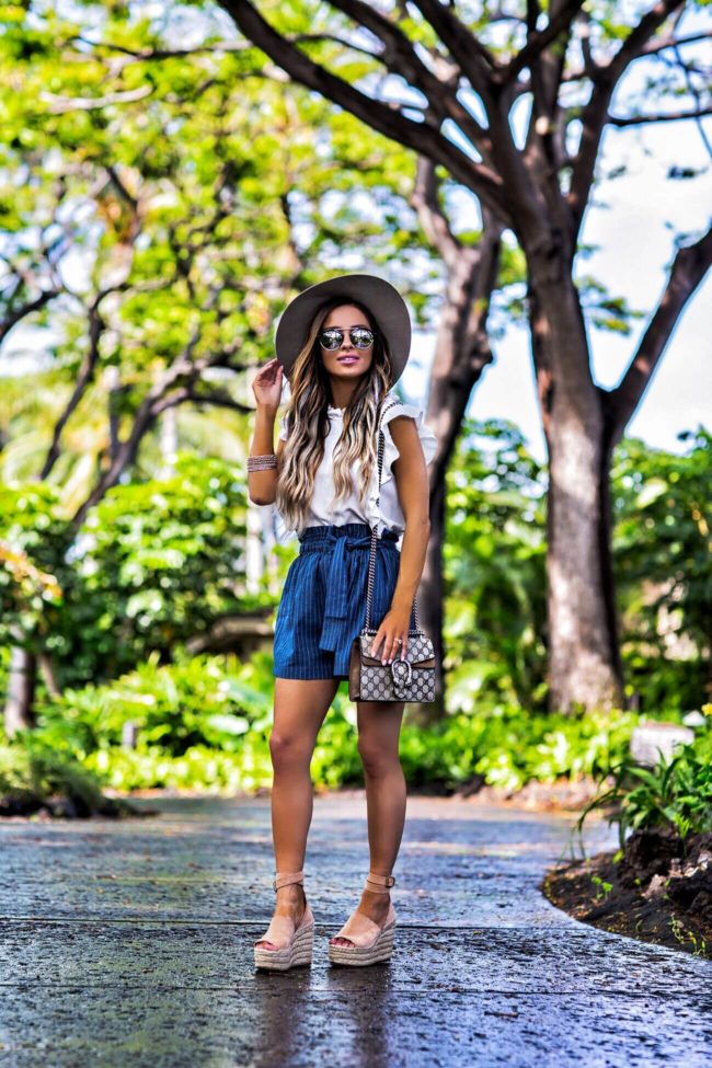 fashion blogger mia mia mine wearing striped shorts and a white crop top in hawaii
