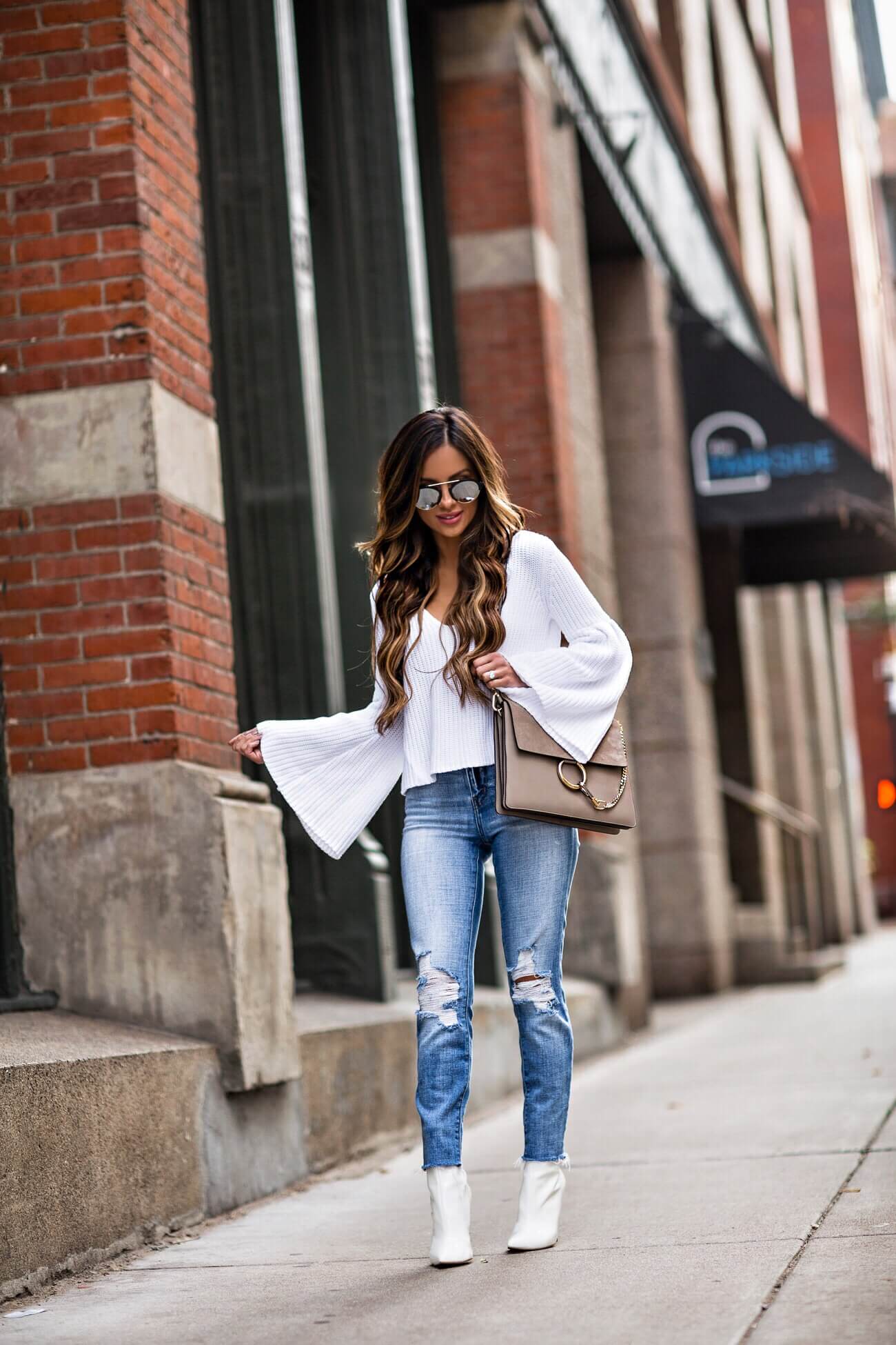 mia mia mine wearing a white bell sleeve sweater and a chloe faye bag