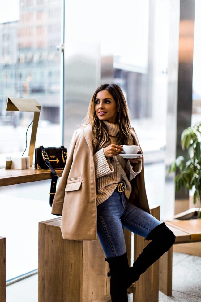mia mia mine at a coffee shop wearing a camel jacket and gucci belt
