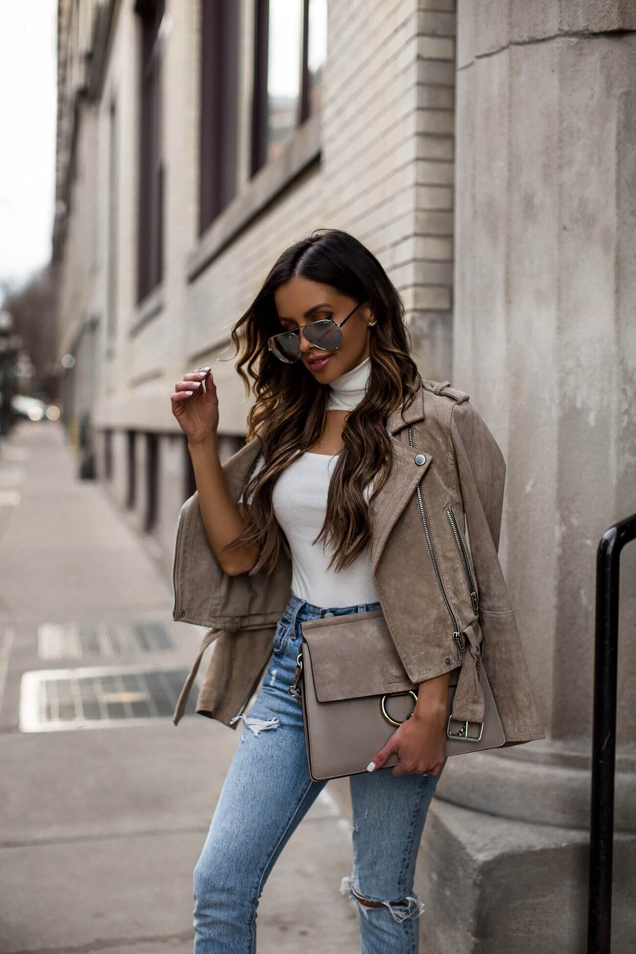 fashion blogger mia mia mine wearing a white bodysuit and blank nyc suede moto jacket