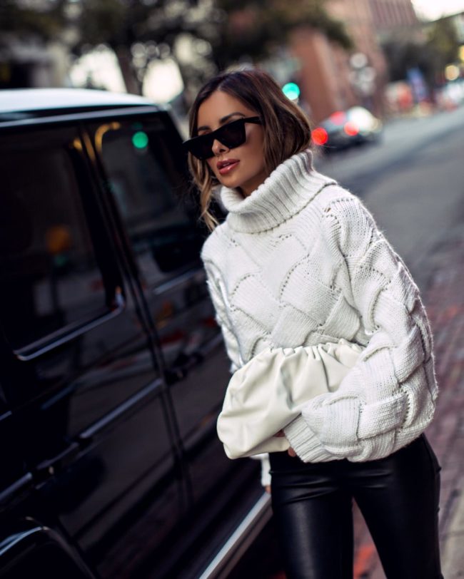 fashion blogger mia mia mine wearing a white chunky knit sweater and a bottega veneta white pouch