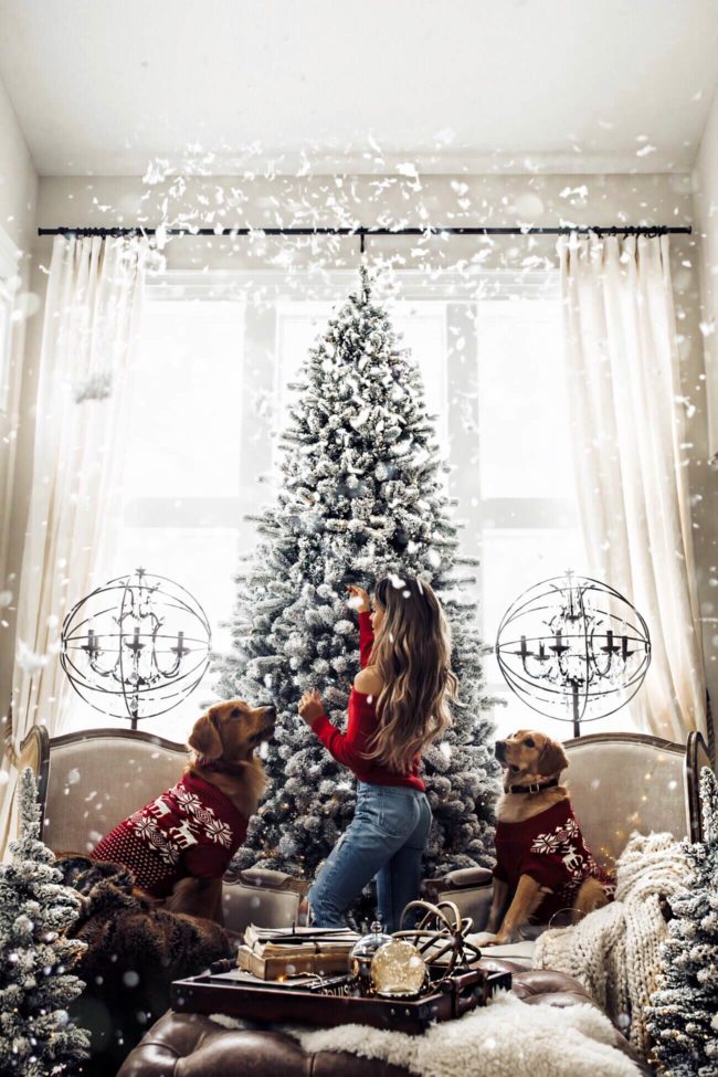 fashion blogger mia mia mine wearing a red off the shoulder sweater in front of king of christmas tree
