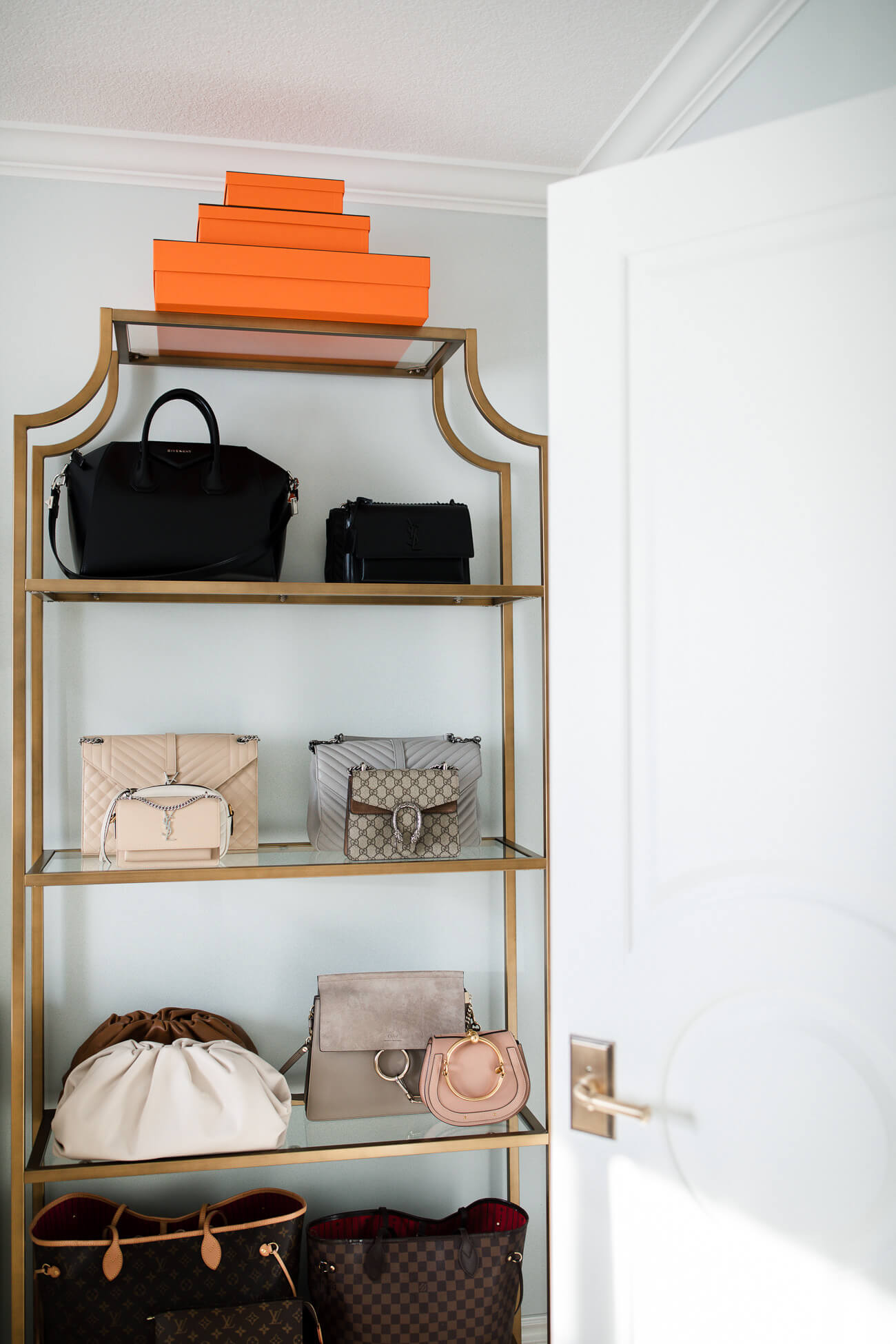 gold etagere bookcase displaying handbags 