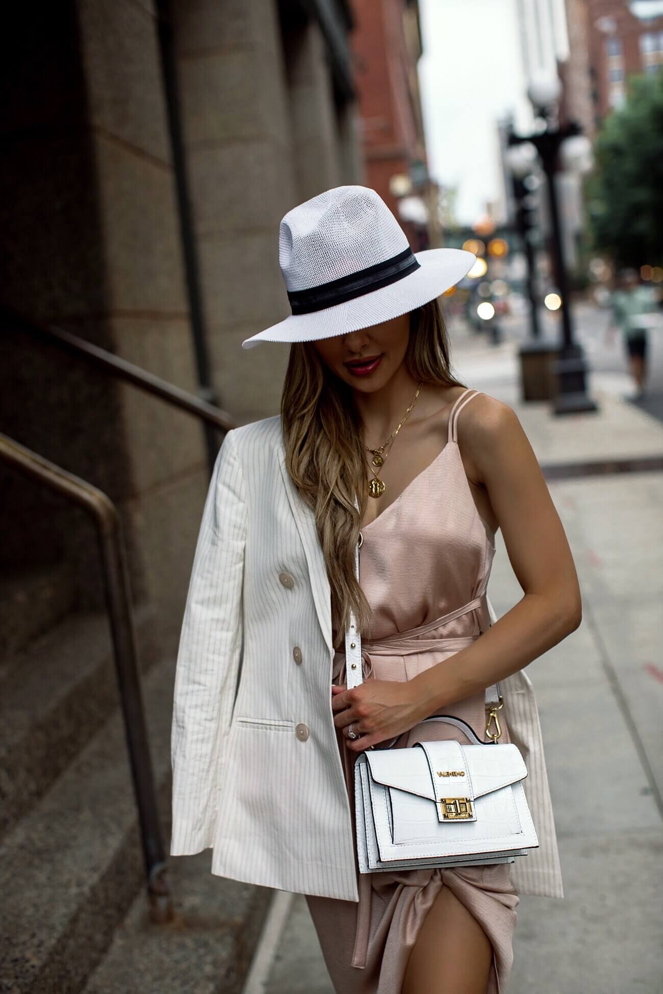 fashion blogger mia mia mine wearing a pink silk dress and a white blazer