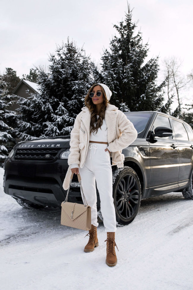 fashion blogger mia mia mine wearing a white loungewear set and a shearling moto jacket