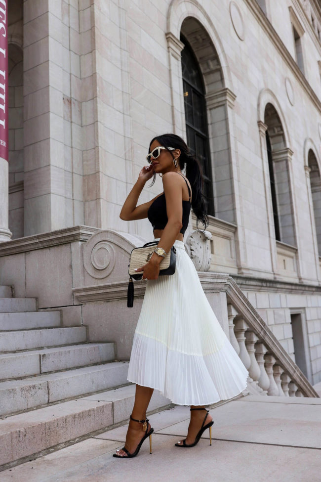 fashion blogger mia mia mine wearing a white pleated skirt and tom ford bralette